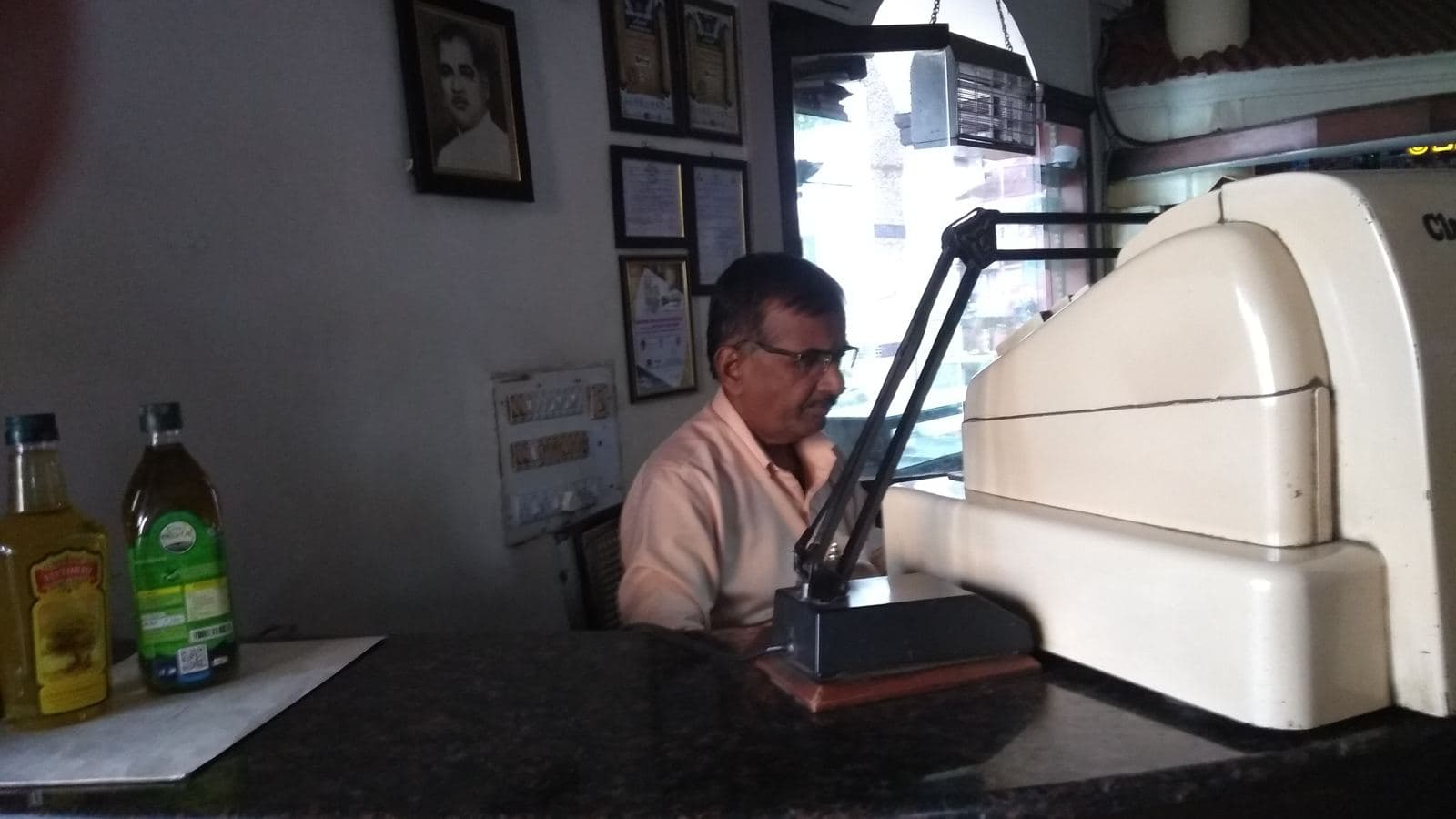Restaurant owner at the cash counter beside an old cash register