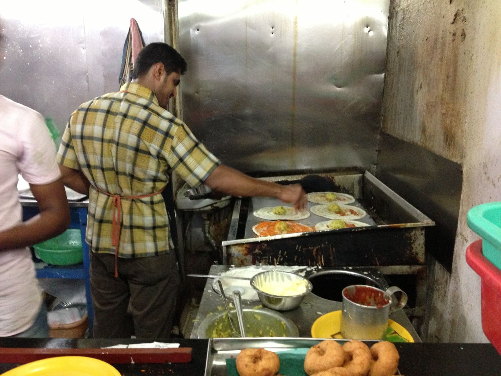 Cook making dosas on a hot griddle in a restaurant kitchen