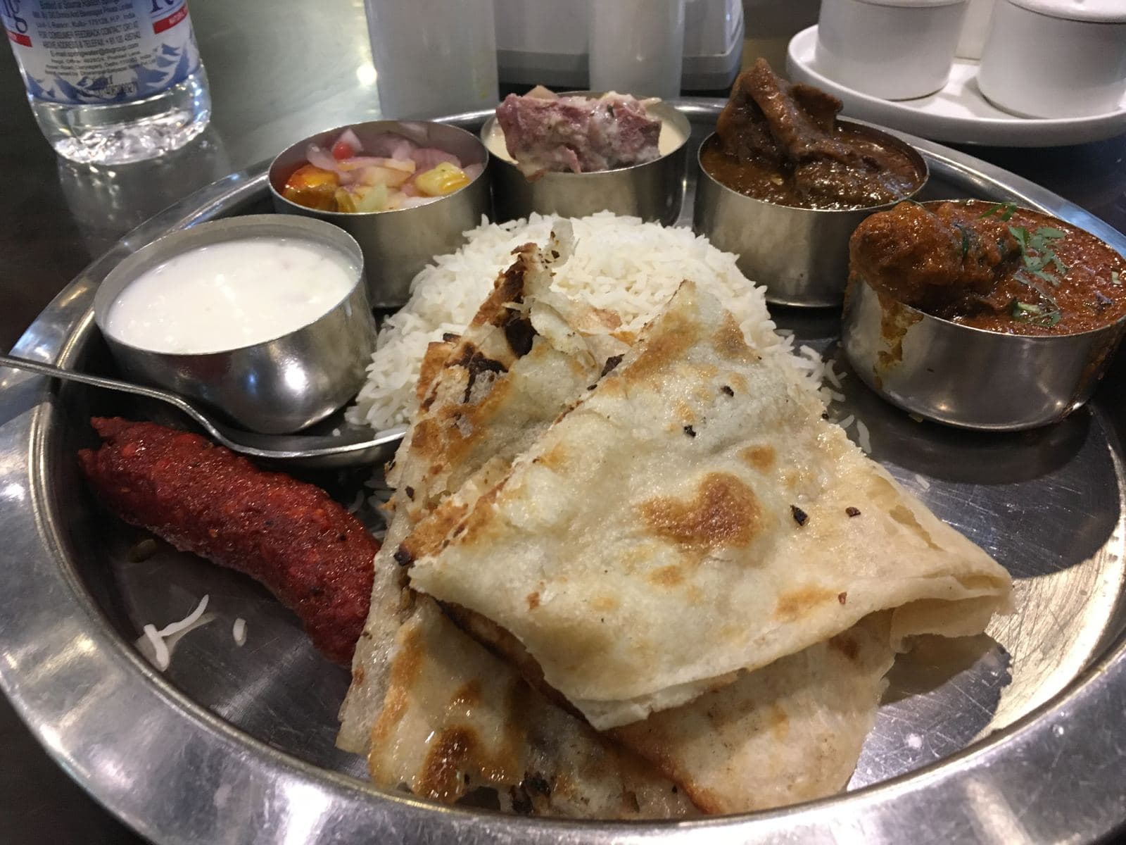 Steel thali with roti, rice, curries and raita